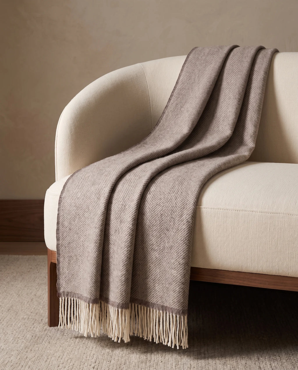 Plaid Denver Beige à chevrons, drapé sur un fauteuil crème — mise en scène