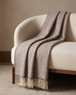 Plaid Denver Beige à chevrons, drapé sur un fauteuil crème — mise en scène