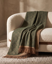 Plaid Venezia Feuille vert et camel, drapé sur un canapé crème — mise en scène